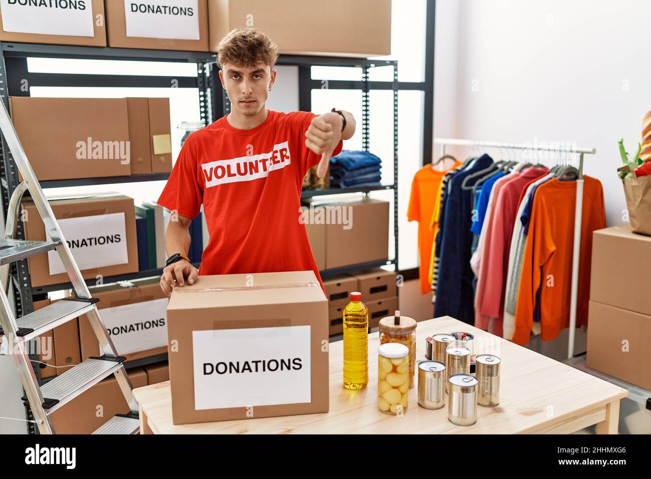 Young caucasian man volunteer holding donations box looking unhappy and ...