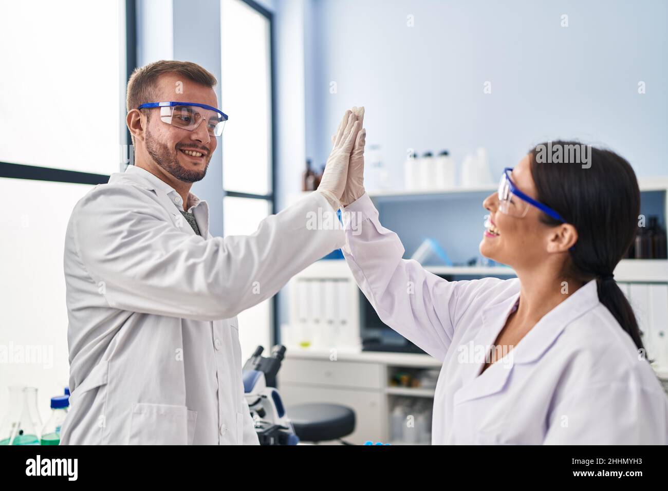 Man and woman scientist partners high five with hands raised up at ...