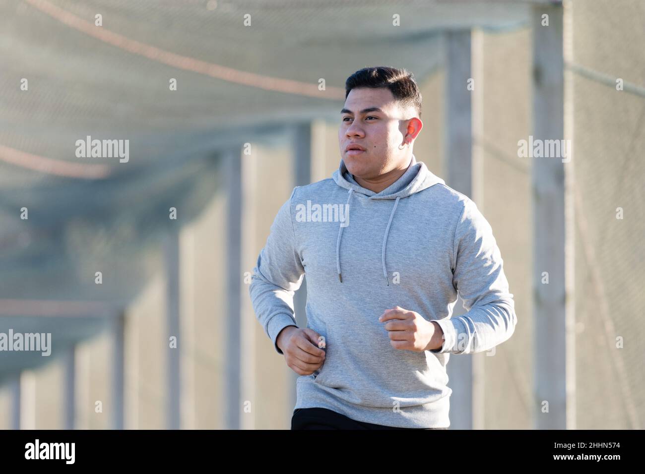 Latin runner jogging and wearing a hoodie Stock Photo