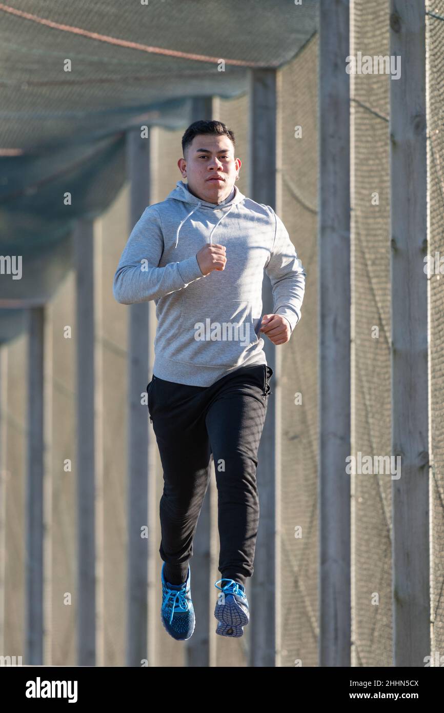 Young latin man running through a walkway Stock Photo