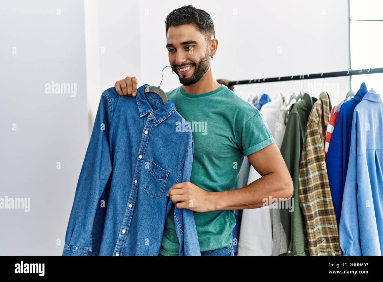 Young arab man customer smiling confident shopping at clothing store ...