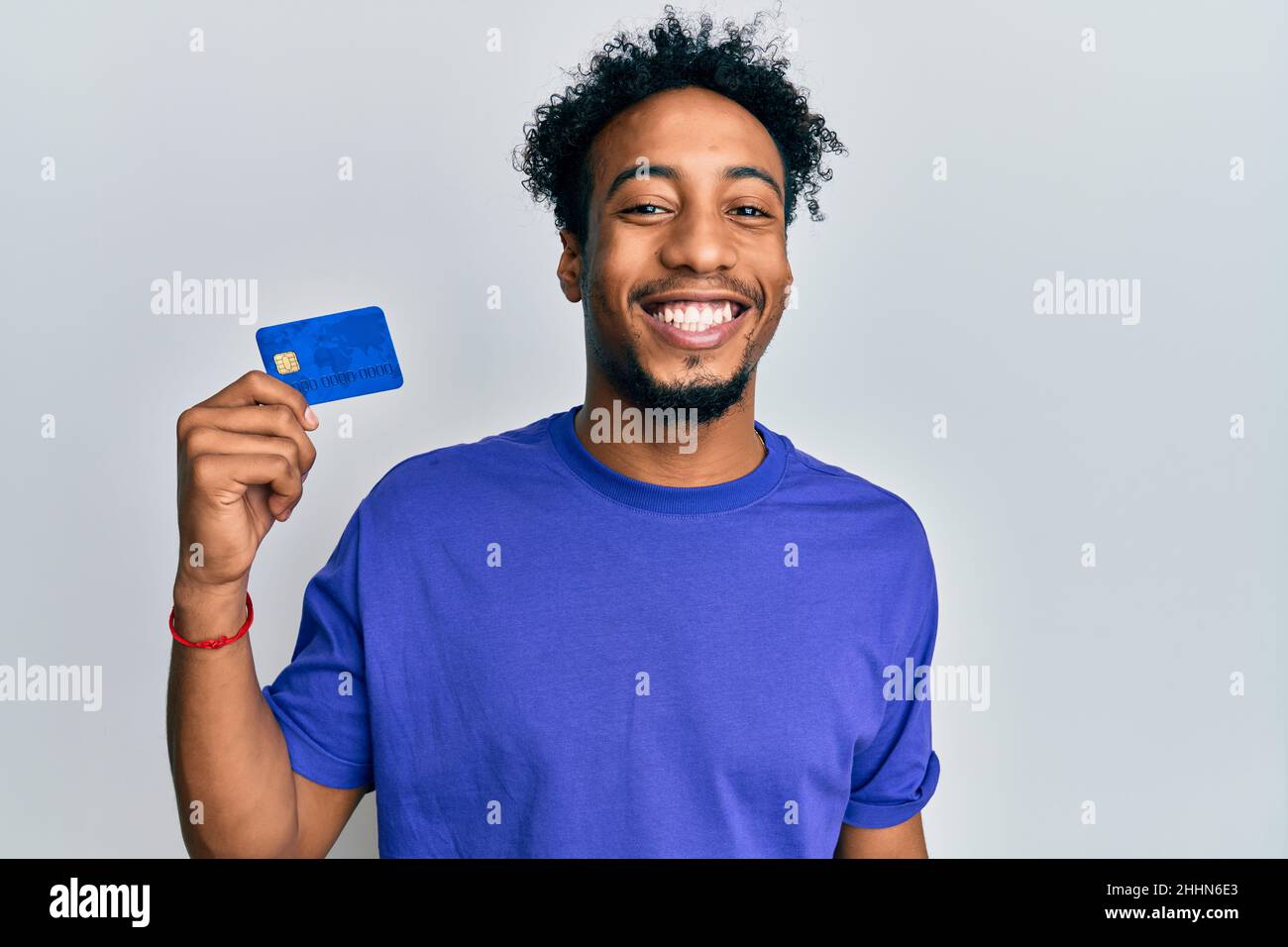 Young african american man with beard holding credit card looking ...