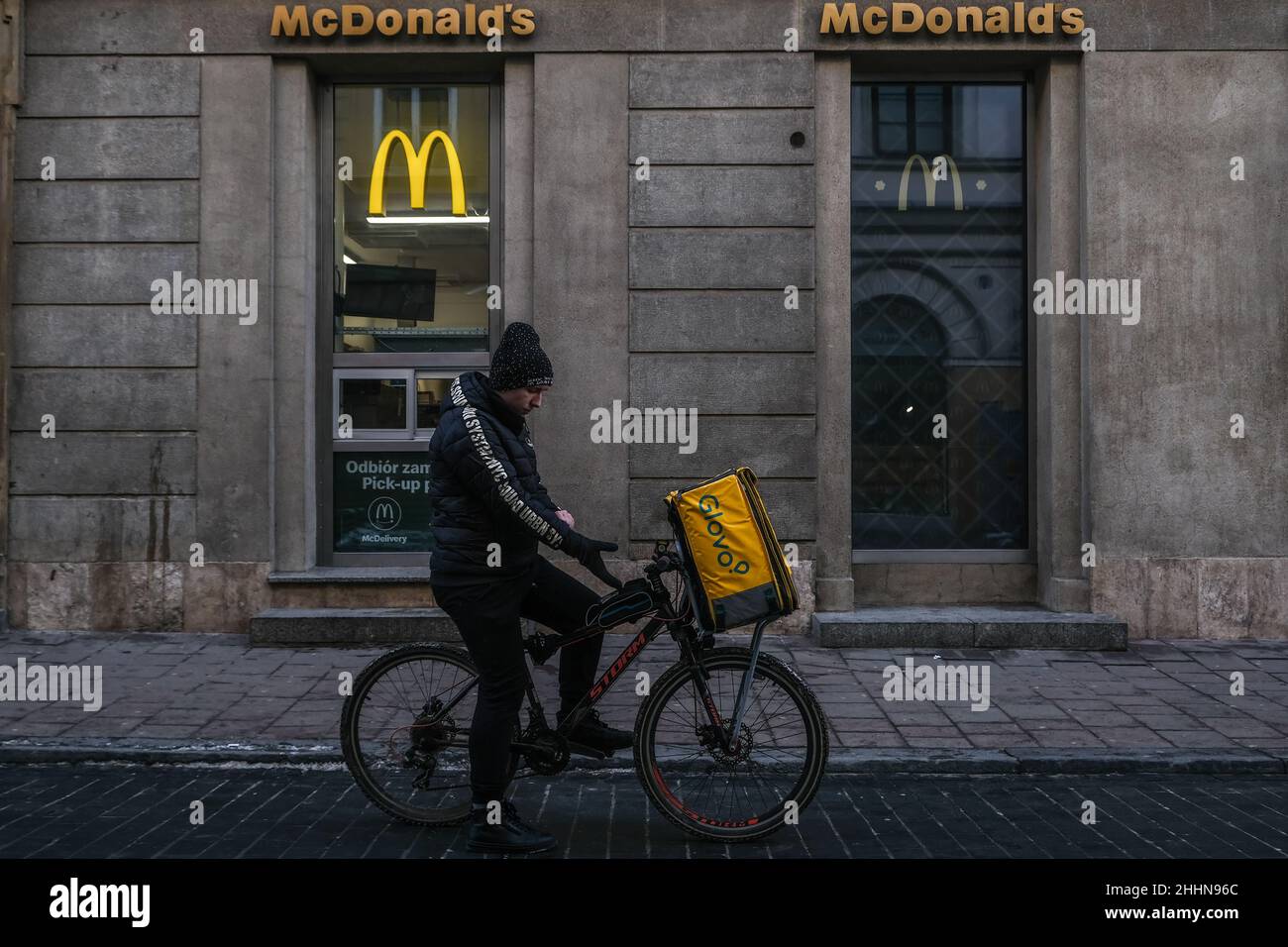 A glovo food delivery worker seen in front of a McDonald's fast food
