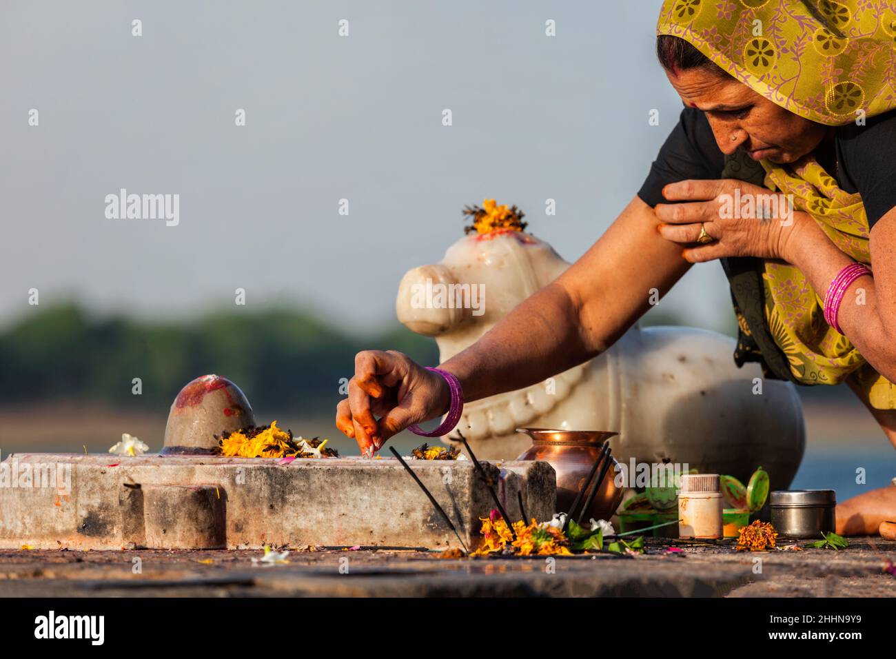 Indian woman performs morning pooja on holy river Narmada ghats Stock Photo