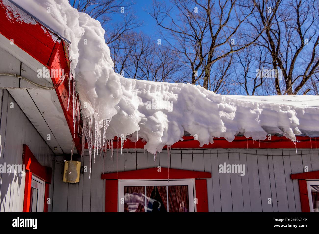 Snow and icicles on a building roof in the spring Stock Photo