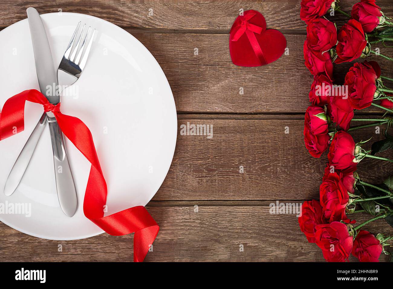Valentines day table setting with plate, fork, knife, red heart, ribbon ...