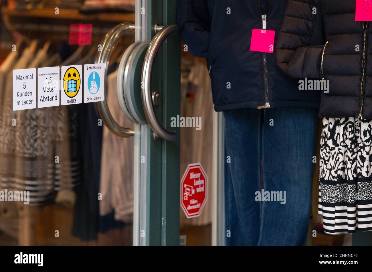 Dachau, Germany. 25th Jan, 2022. Stickers reading 'Maximum 5 customers in the store, 1.5 meters apart, and please disinfect hands' can be seen on the door of one store. Credit: Sven Hoppe/dpa/Alamy Live News Stock Photo