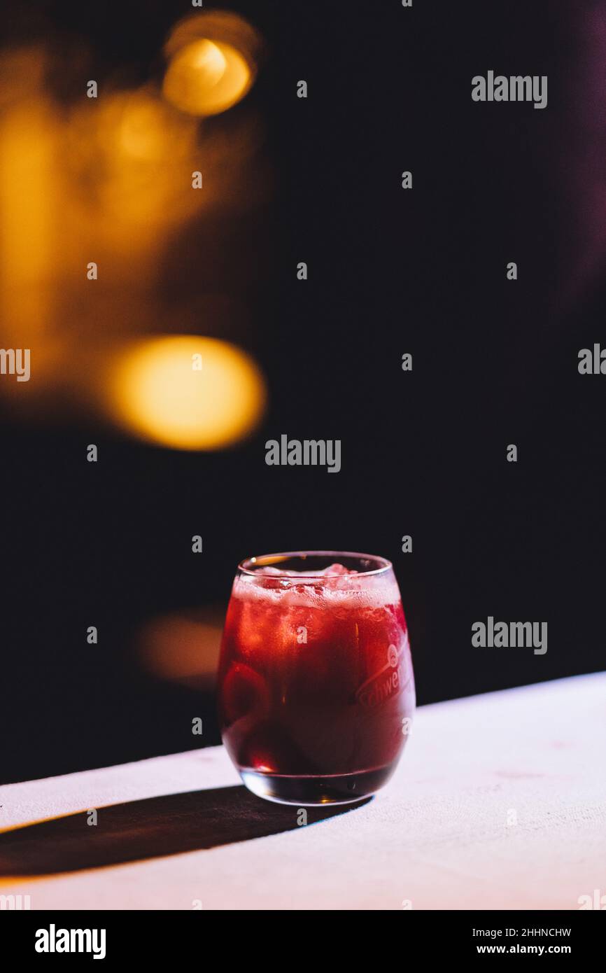 A vertical shallow focus shot of a red drink in a glassy cup on a table Stock Photo