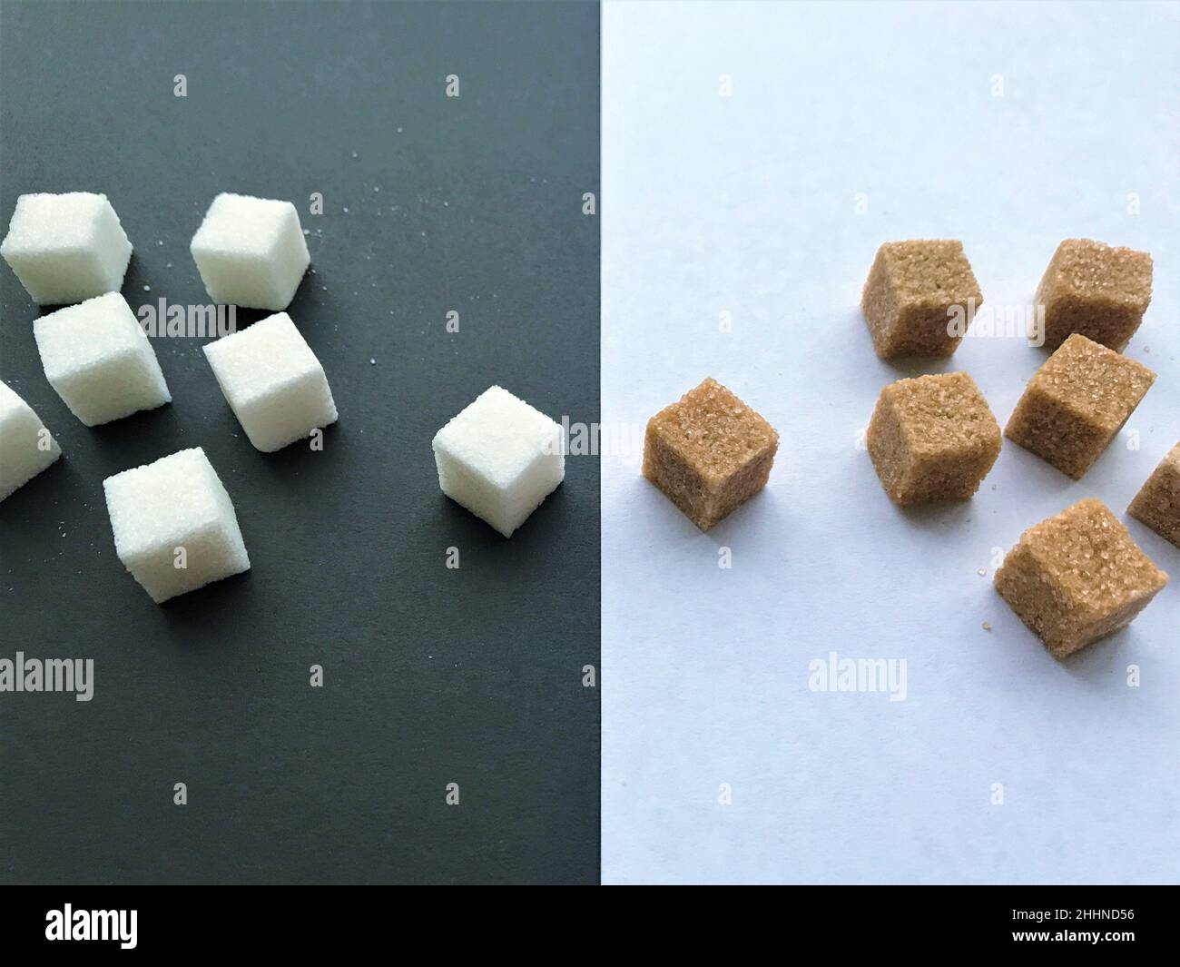 Confrontation groups of sugars: pieces of refined white on a black background and cane brown on a white background opposite each other. Stock Photo
