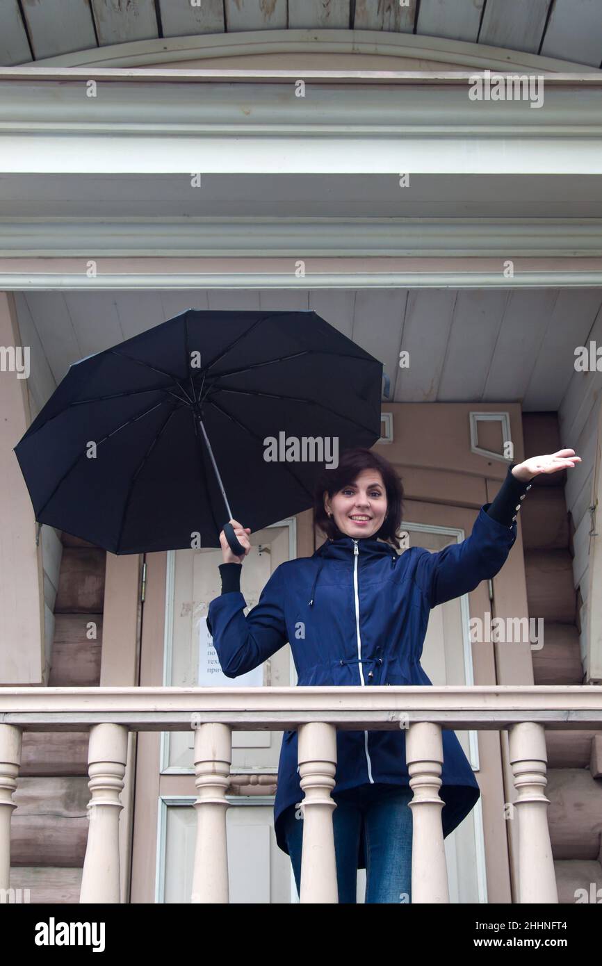 A happy woman with  black umbrella in her hands old wooden building. Stock Photo