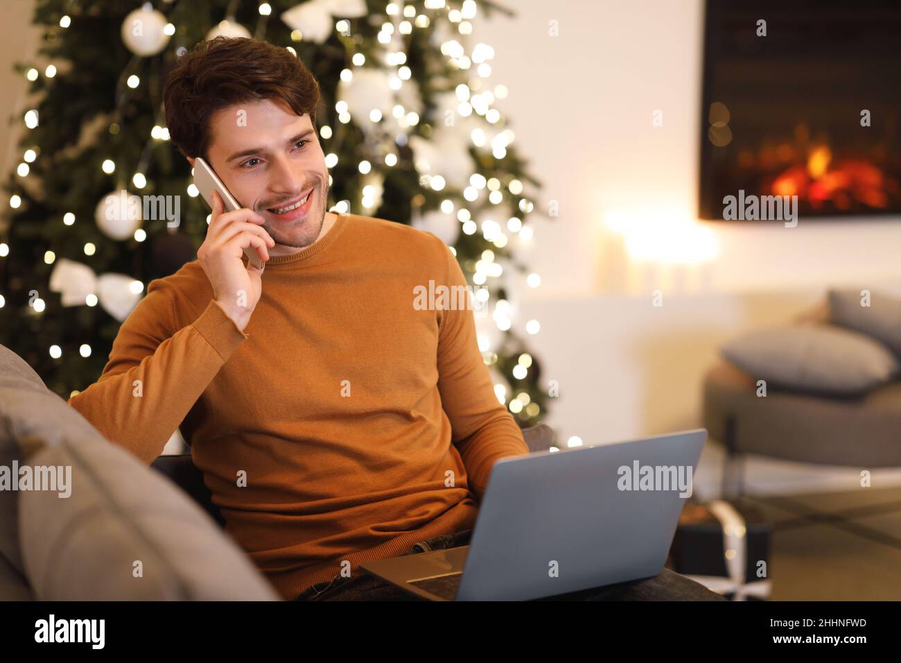 Cheerful man working and talking on cellphone using pc Stock Photo