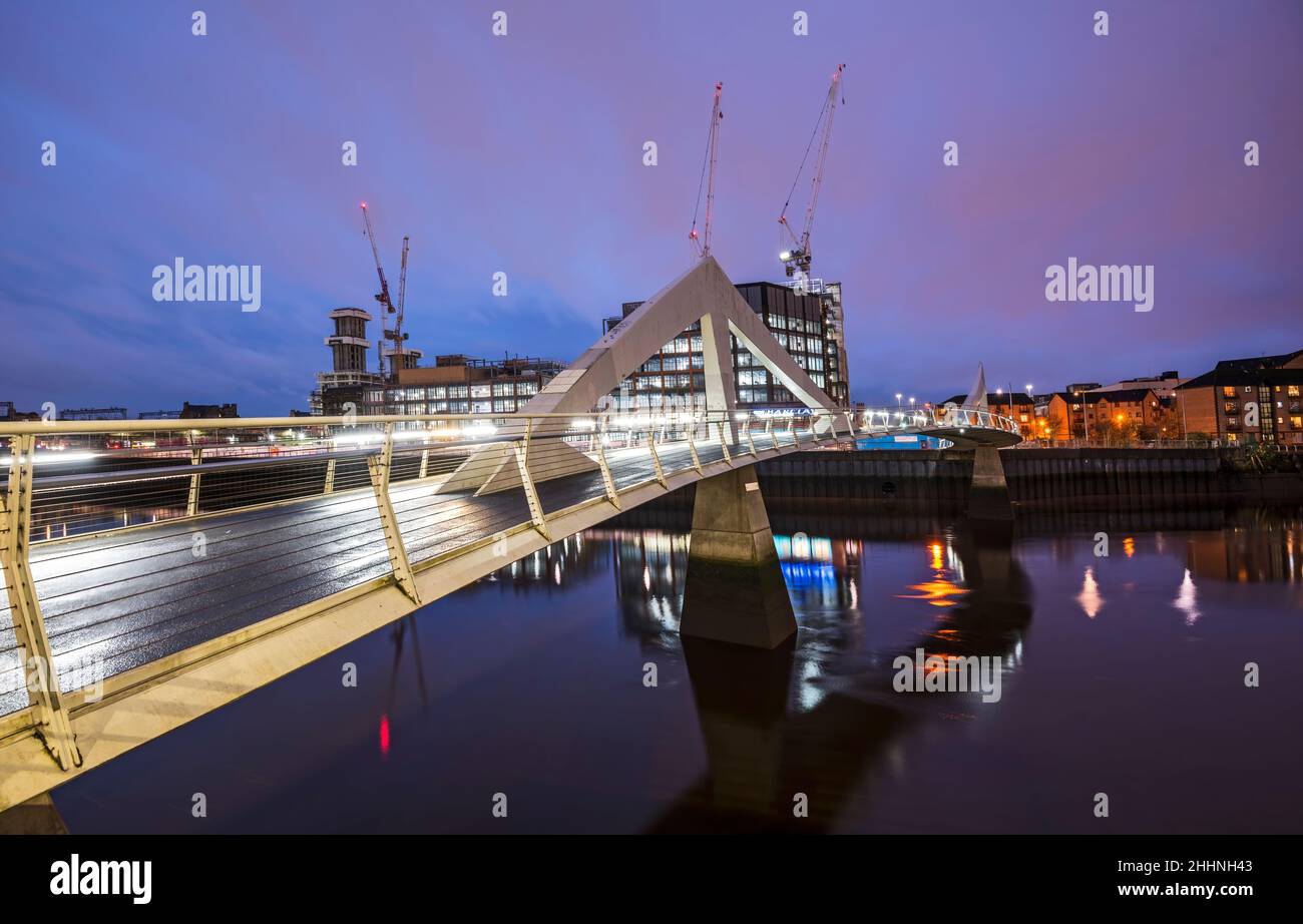 Night picture of the Tradeston (Squiggly) Bridge over the River Clyde on calm winter evening. Stock Photo