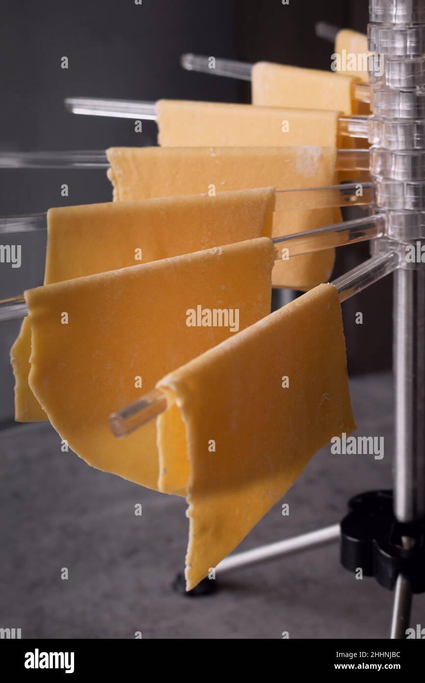 Close-up of fresh homemade pasta hanging on a pasta dryer rack ready to be used for lasagna. Selective focus Stock Photo