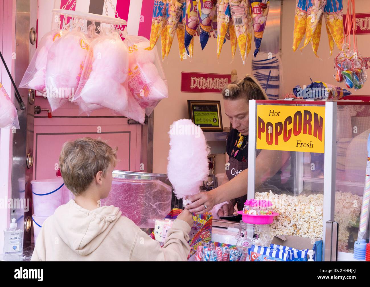Buying candyfloss; a child buying candy floss aka cotton candy at a sweet stall at the fair, Hertfordshire UK, example excess sugar in diet Stock Photo
