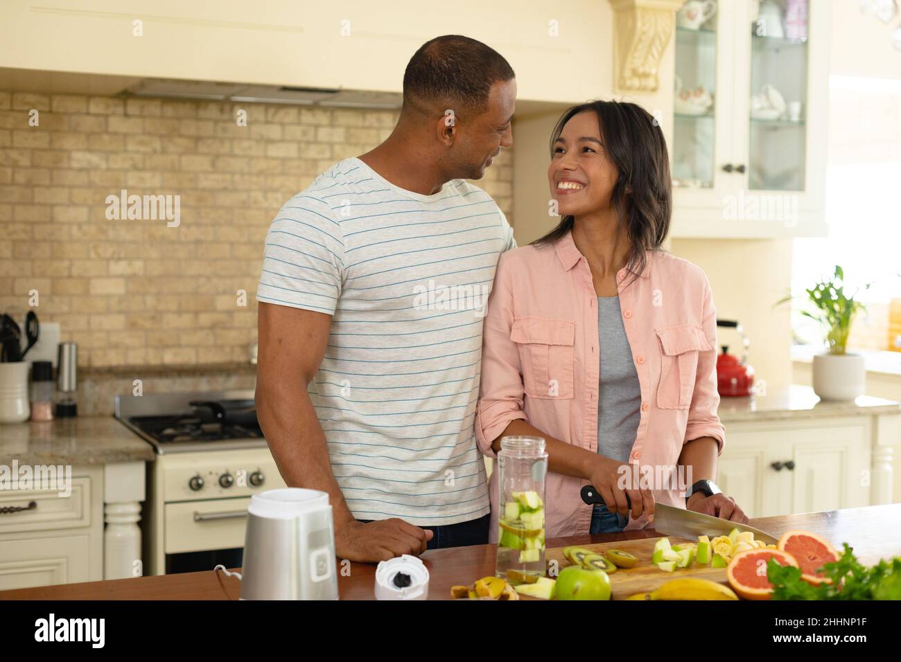Smiling young african american couple romancing while cooking food ...