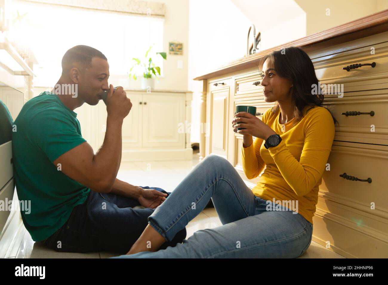 Smiling young african american couple drinking coffee while sitting on ...