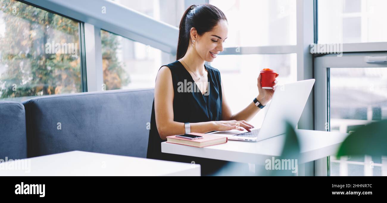 Cheerful female remote worker using laptop in cafe Stock Photo