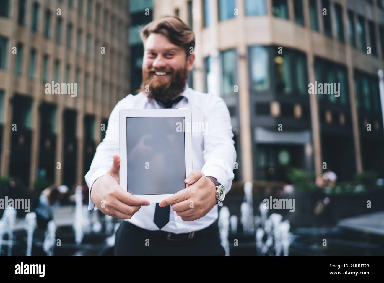 Happy businessman showing tablet screen on street Stock Photo