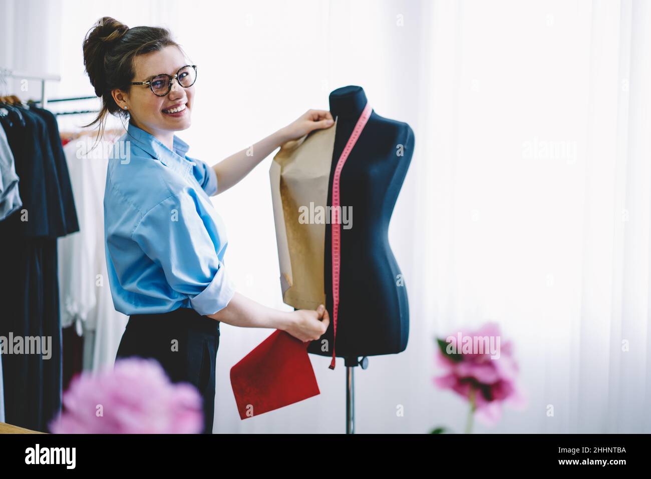 Positive female professional taking measurements on mannequin Stock Photo