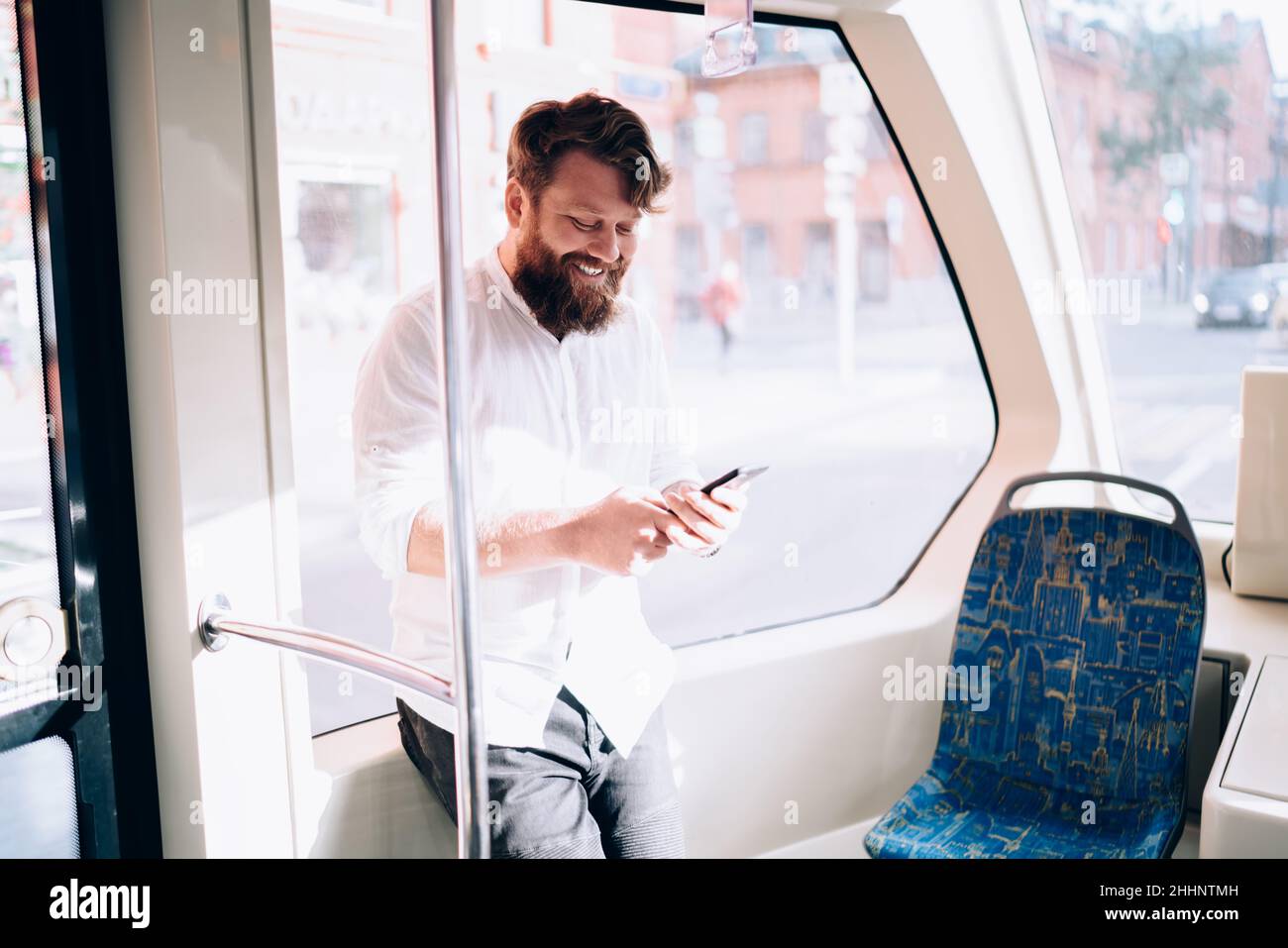 Bearded man using phone in bus Stock Photo
