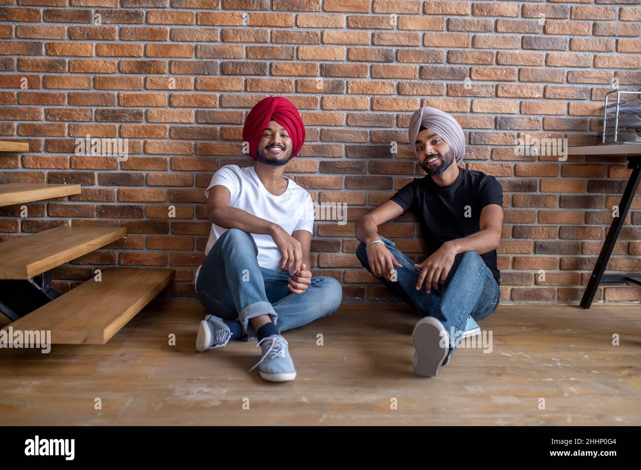Two young men sitting on the floor at home and looking relaxed Stock ...