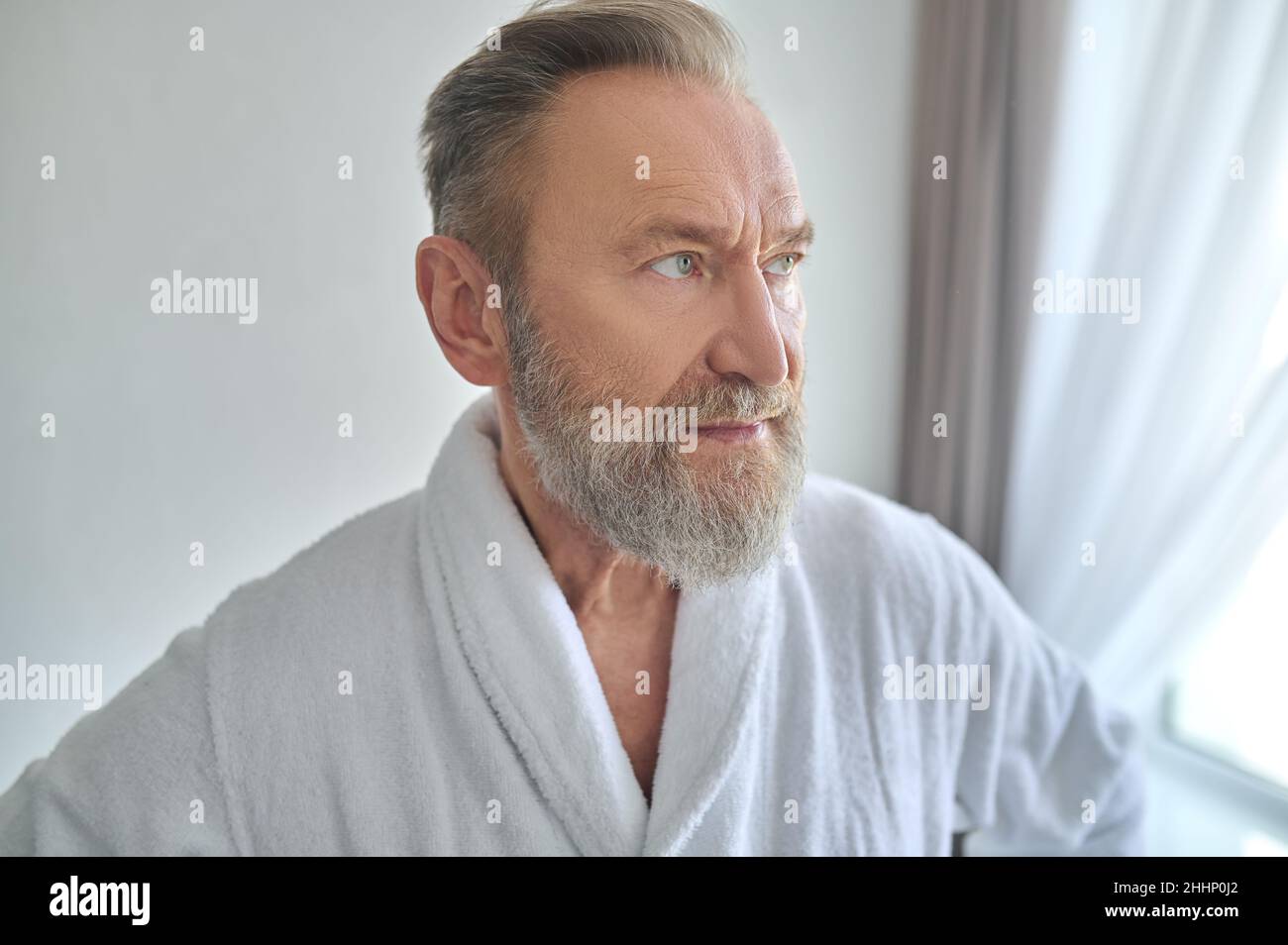 Thoughtful man in the towelling robe looking away Stock Photo