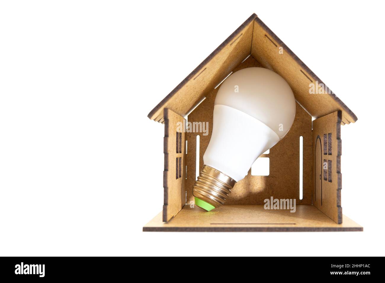 Energy efficient light bulb inside a miniature wooden house model isolated on white. Cutting down bills with led lamps. Stock Photo