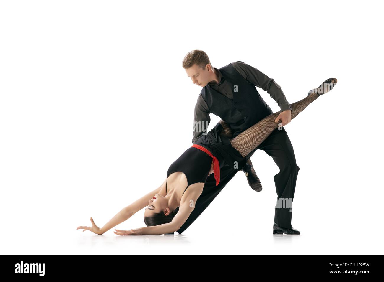 Flexible young couple dancing Argentine tango isolated on white studio background. Artists in black stage costumes Stock Photo