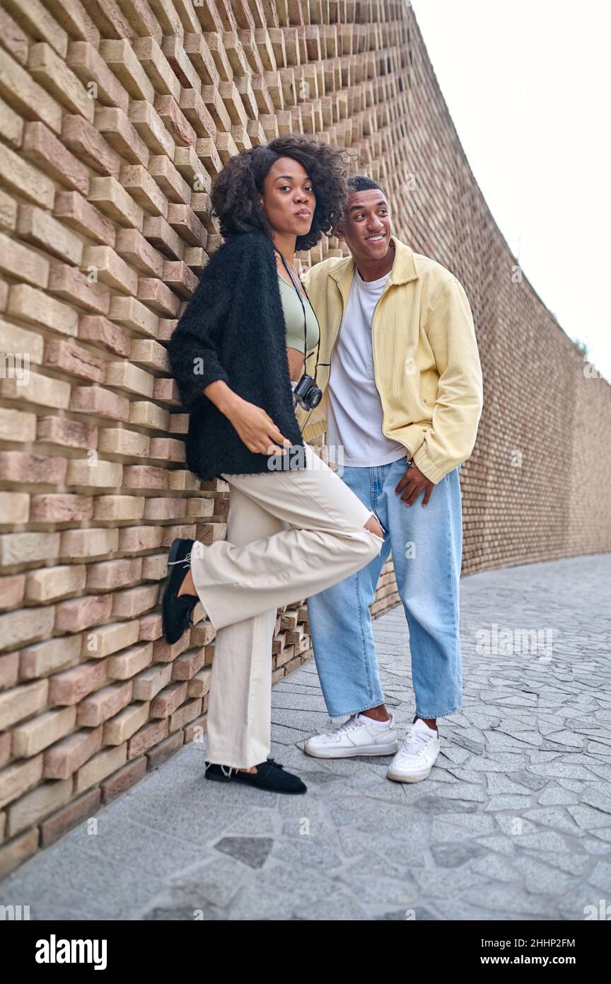 Woman and man standing leaning against brick wall Stock Photo - Alamy
