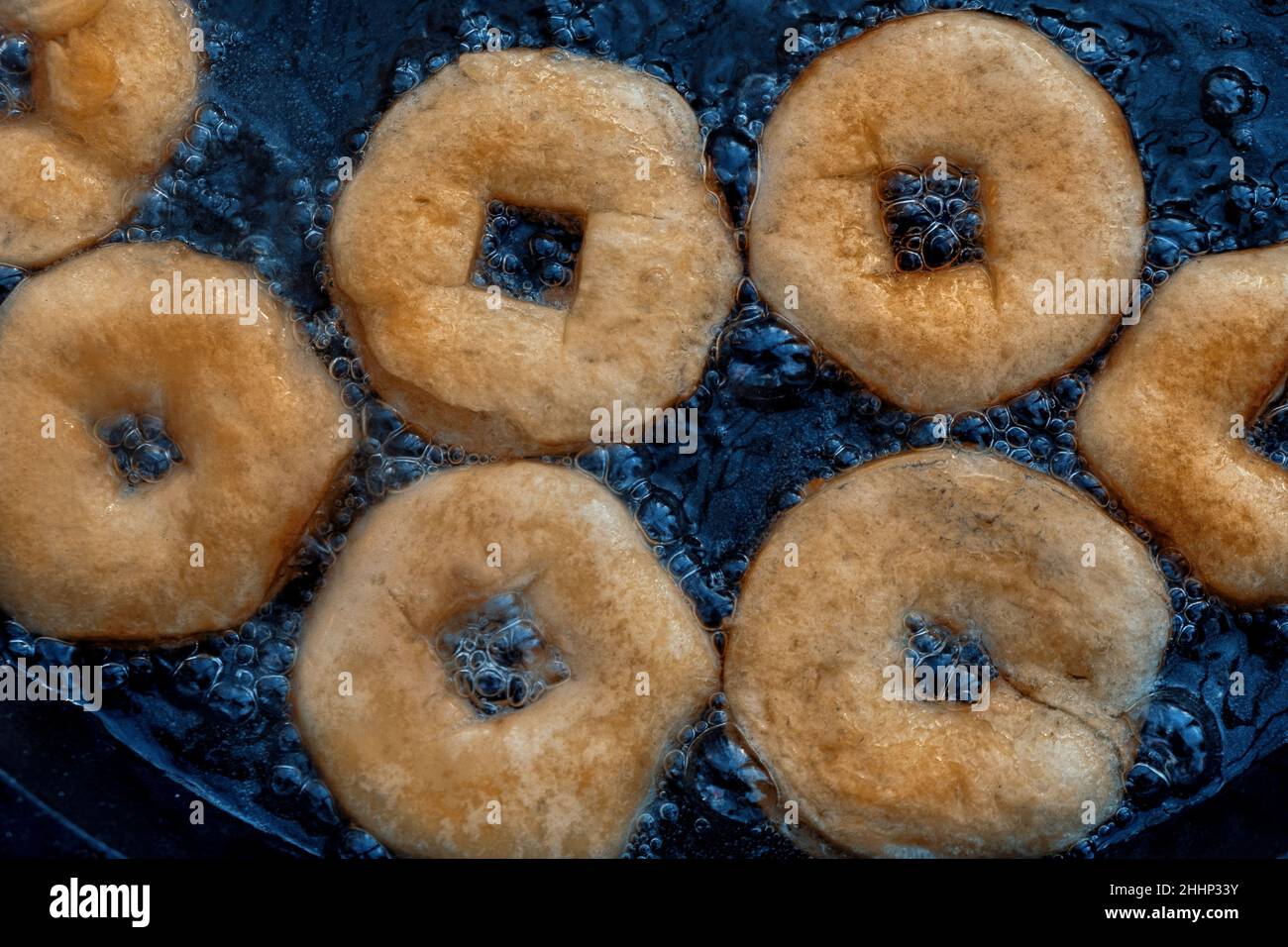 Homemade donuts frying in cast iron skillet outdoors. Stock Photo