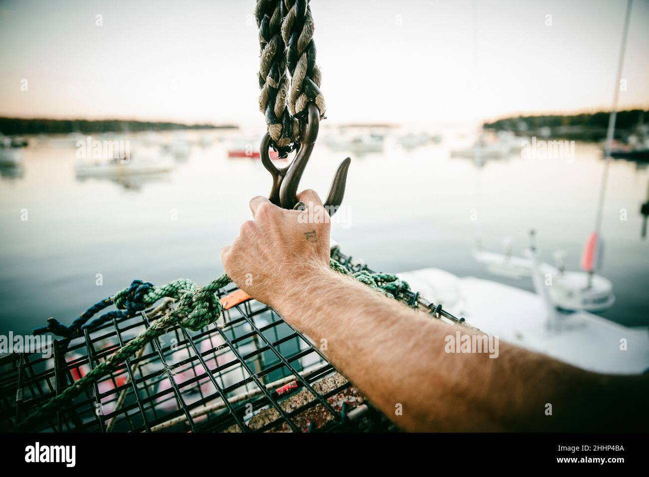 Lobster fisherman holding a lobster cage on a boat in Owl's Head, Maine Stock Photo