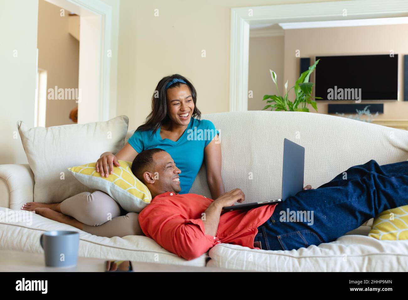 Happy african american couple watching laptop together on sofa at home ...