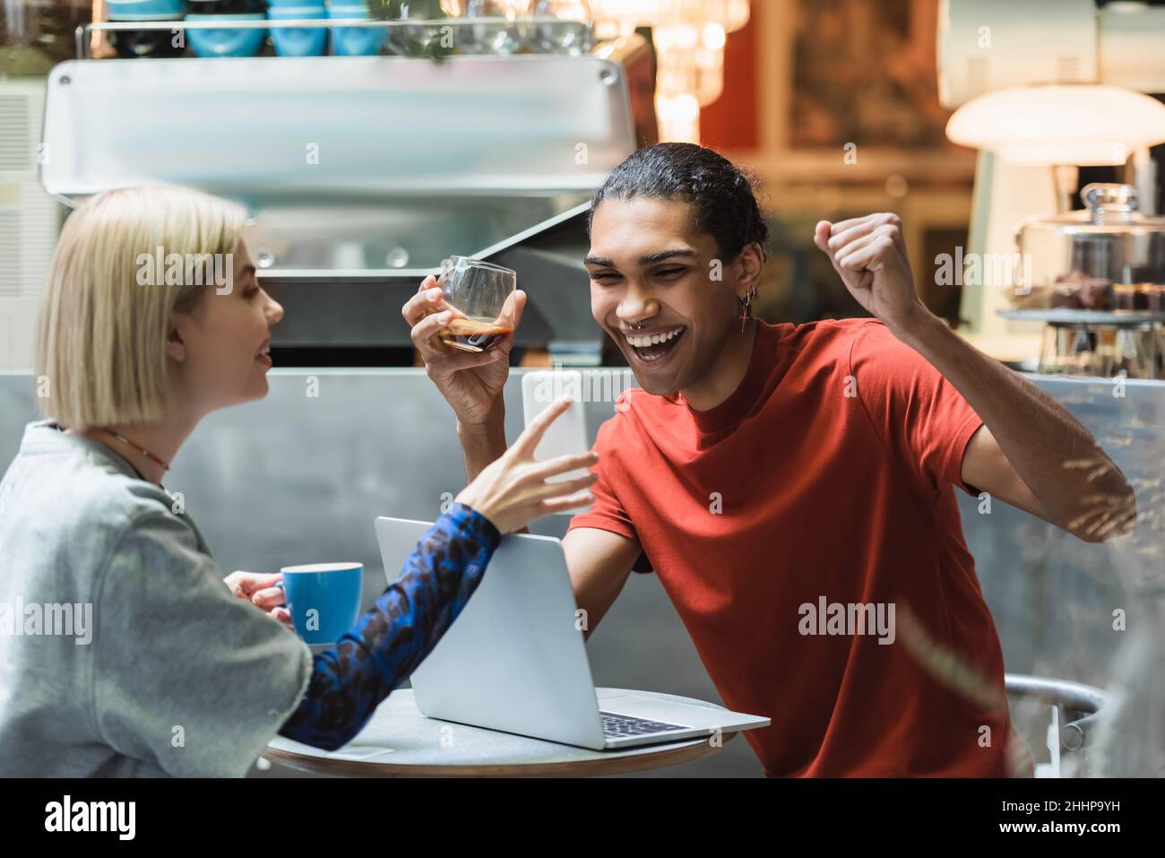 Excited african american freelancer holding coffee near girlfriend and