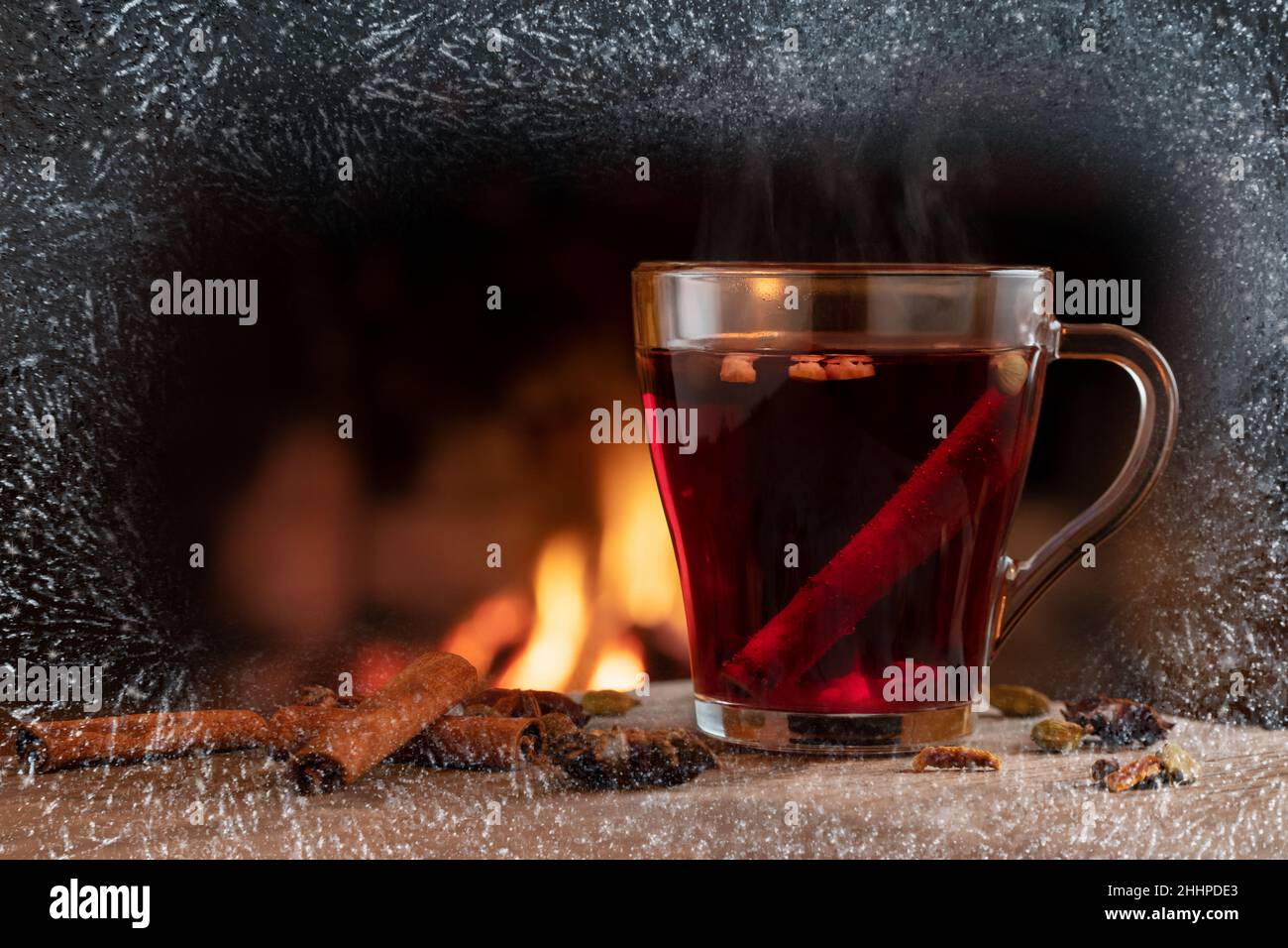Glass mug with hot mulled wine by the burning fireplace Stock Photo