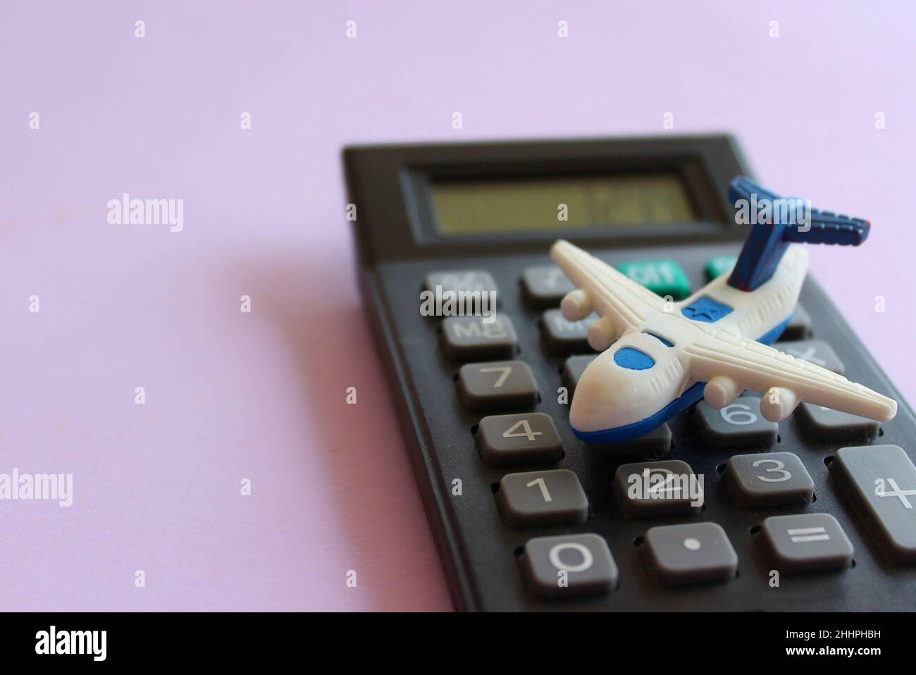 Selective focus image of toy plane and calculator on purple background. Travel cost calculation concept. Stock Photo