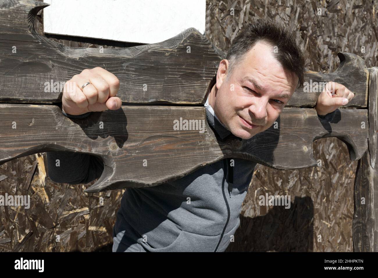 Portrait of unhappy man in wooden pillory outdoor Stock Photo