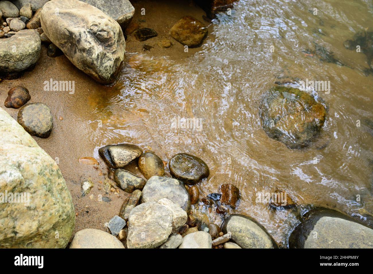 closeup view of riverbank, stones and sand next to the water, riverside
