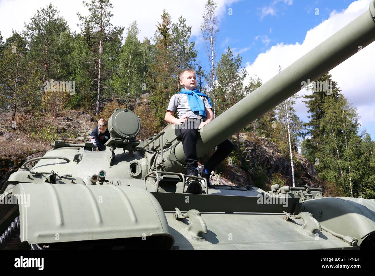 Kid sitting on gun of t-62 tank at Gora Filina, Karelia Stock Photo