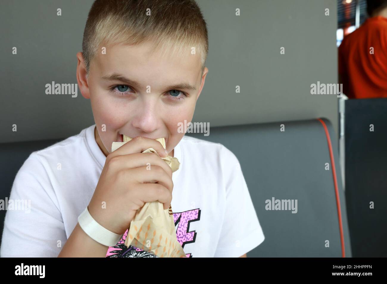 Hungry kid eating Hot Dog in restaurant Stock Photo