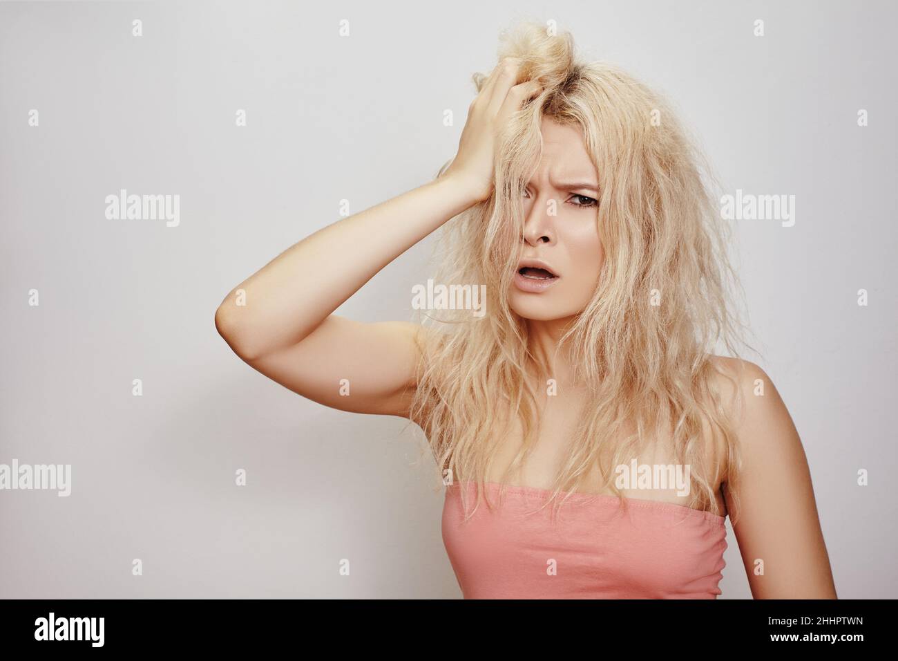 Beautiful woman with messed up hair. Unhappy grimacing face. Blond