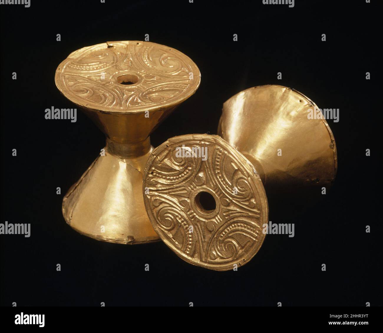Pair of Ear Spools 100 B.C.–A.D. 800 Calima-Yotoco Calima leaders of the Yotoco period in the Cauca Valley region of southwest Colombia wore resplendent regalia in life and in death. These included diadems, pectorals, nose ornaments, and elaborate, multicomponent ear ornaments terminating in large, circular pendants. Biconical or spool-shaped objects with decorated ends such as these were inserted through the earlobes, and large concave disks gold would be suspended through an opening at the center of these with thin gold wires. Made of lightweight hammered gold sheet, the biconical elements p Stock Photo