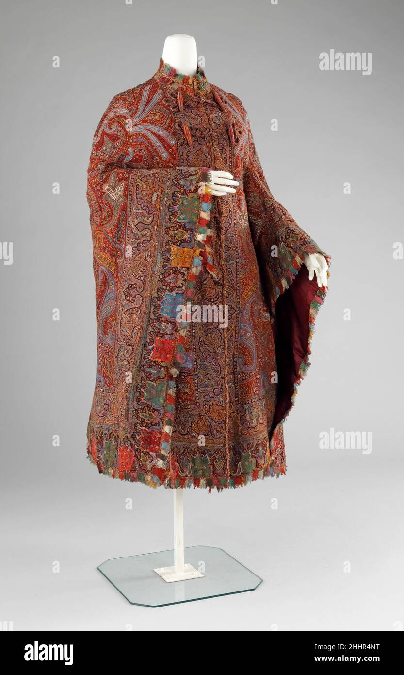 Cloak 1885–89 American In the 1870s shawls lost popularity due to its immense size and the reducing expanse of skirts to help support them. Although some were retained as heirlooms, others were stitched into the more wieldy shape of the cloak or the mantle. This cloak is made from a fine quality embroidered Indian shawl. Embroidered shawls were produced in India to imitate woven shawls because they were easier and faster to make than the woven variety. Embroidered examples have an interesting textural quality about them which lends itself to the highly decorated outerwear of the 1880s.. Cloak Stock Photo