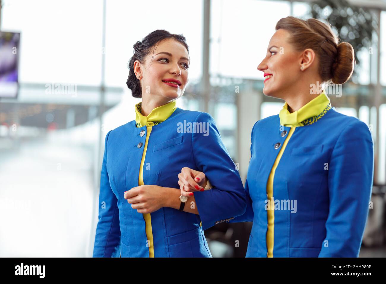 Two flight attendants walking arm in arm at airport terminal Stock Photo Alamy