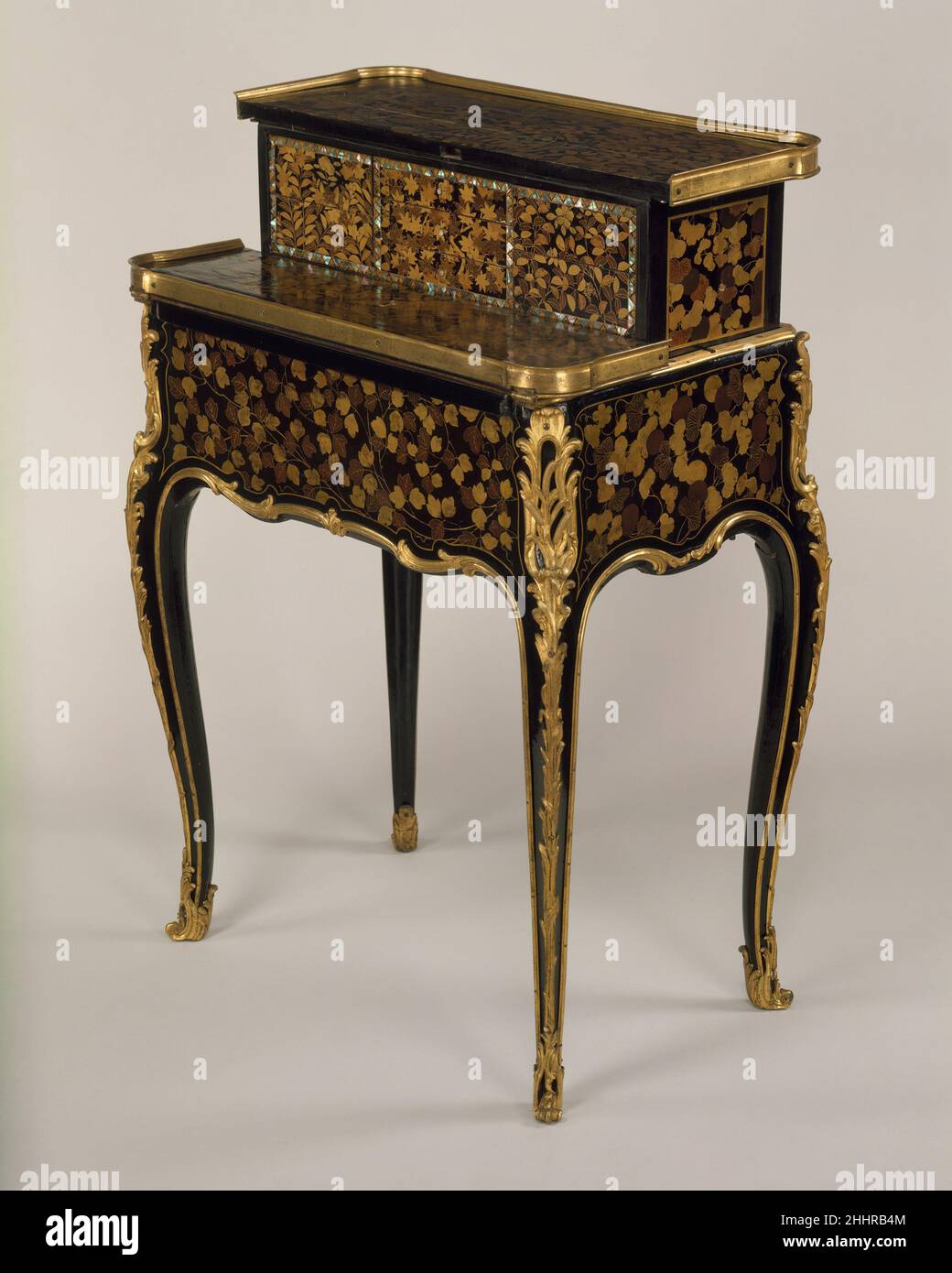 Mechanical table à la Bourgogne ca. 1760 René Dubois Mechanical tables of varying degrees of complexity were popular from the mid-eighteenth century and were made by several prominent ébénistes, in particular Jean François Oeben and Jean Henri Riesener. This table, known as a table à la Bourgogne, is stamped R. DUBOIS and dates to ca. 1760. The elegant curves of the legs and lower edge are emphasized by the delicate mounts. These, in turn, are echoed by the fine gold line delineating the lacquer panels while the gilded mounts encasing the feet add further refinement.The front half of the top o Stock Photo