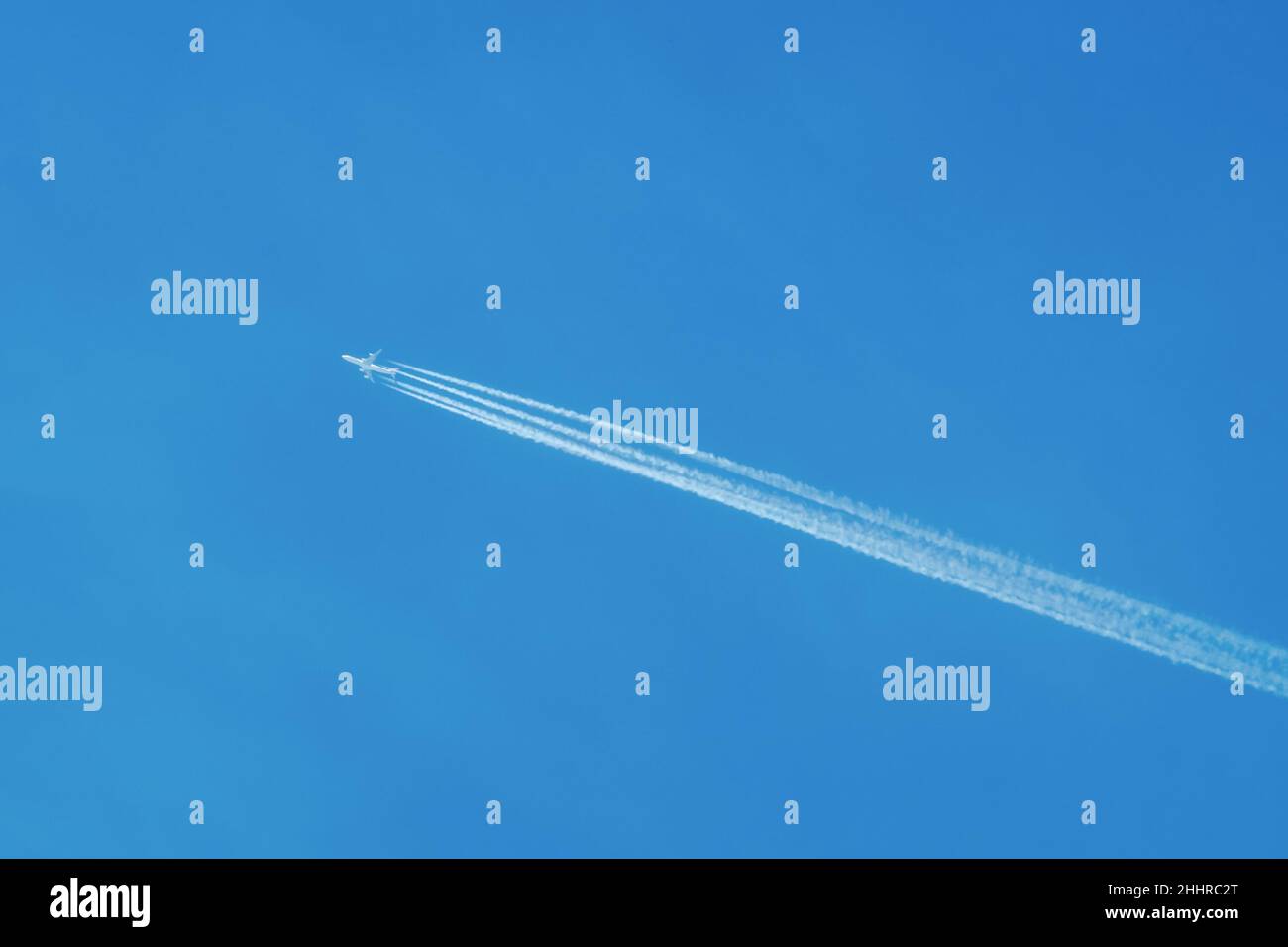 Jet airliner flying high in the sky, leaving contrails in the clear blue sky Stock Photo