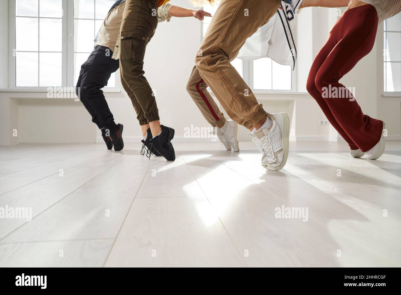 Group of hip hop dancers who together perform stand on toes during rehearsal in dance studio. Stock Photo
