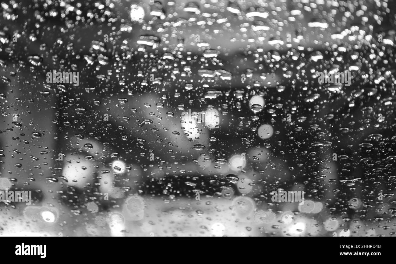 Closeup of raindrops on the car windshield with blurry street at night