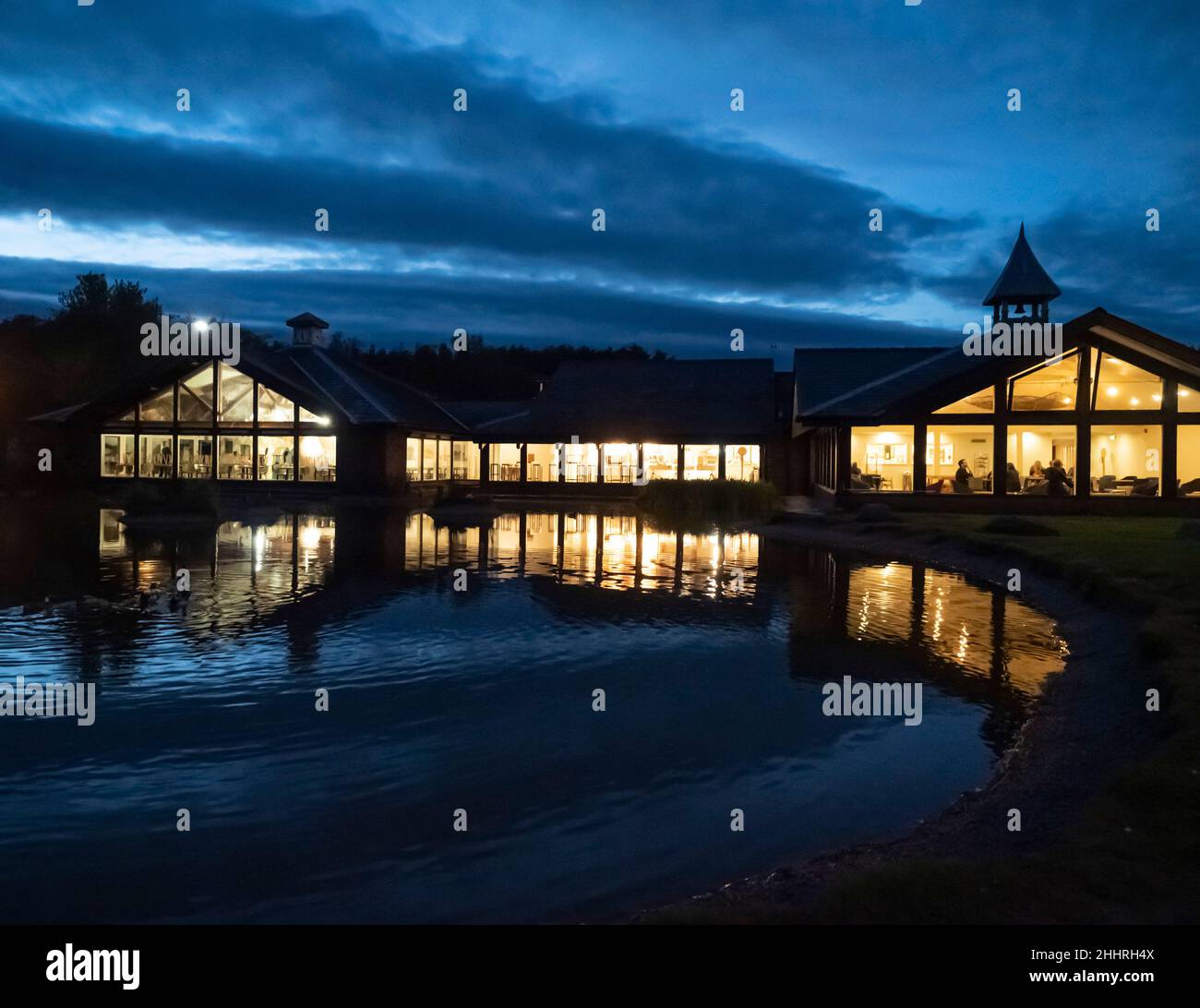 Tebay M6 northbound services near Kendal in Cumbria, at dusk with the restaurant lights and the pond. Stock Photo
