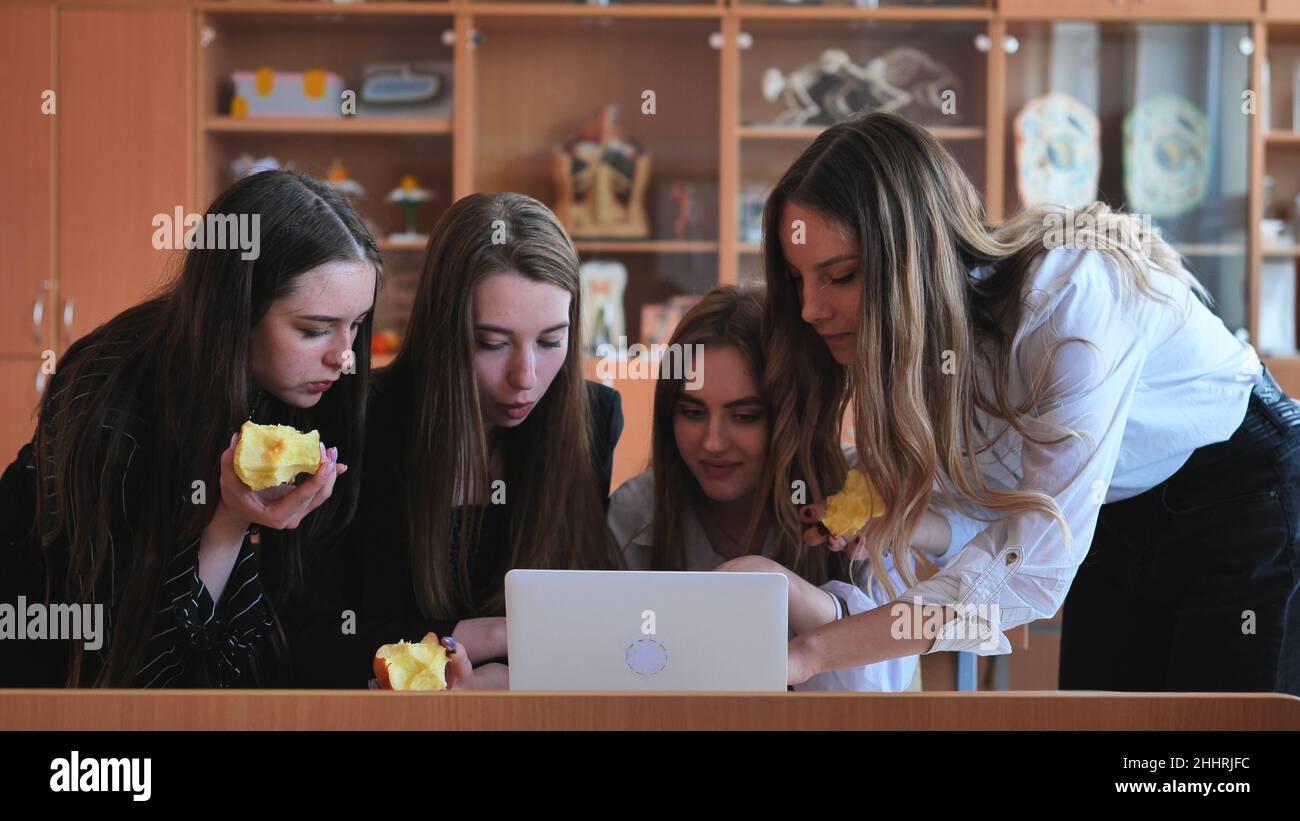 Schoolgirls friends working together in class with a laptop and eating ...