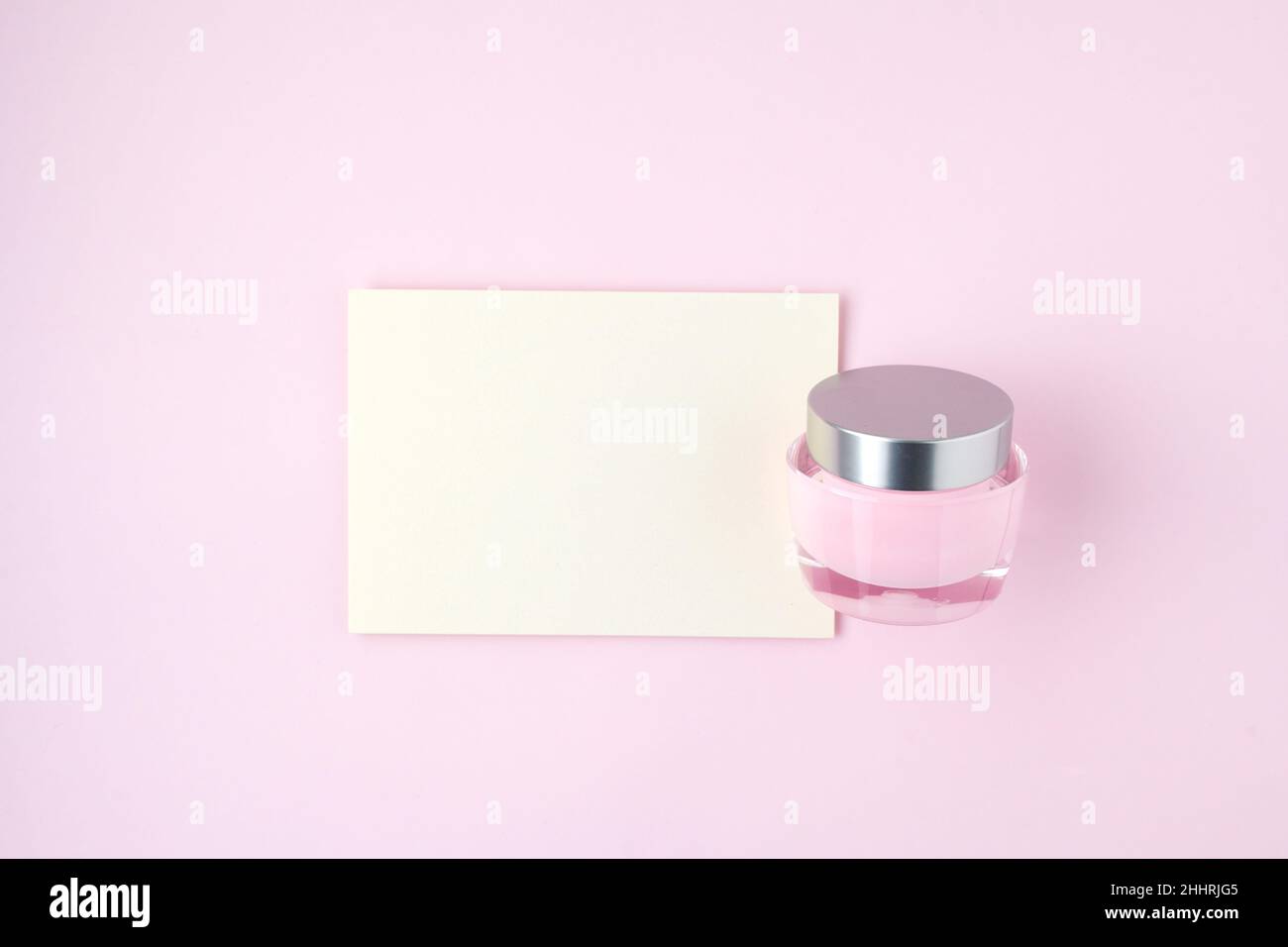 spring flat lay with paper sheet and facial creme isolated on pink ...
